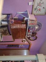 Photo showing large round copper boiler with brass handles, part of a shelf with decorative items.