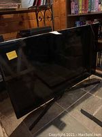 Samsung 40-inch flat screen TV with stand and reflective screen surface seen from the front and side.