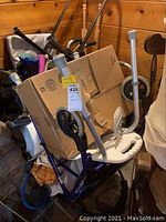 Purple rollator walker with box on seat and other equipment behind