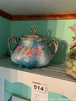 Lidded blue and milk glass floral porcelain jar with gold handles and rim