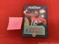 Front photo of Sega Genesis Joe Montana II Sports Talk Football game cartridge with case on red background and pink sticky note with number 26.