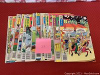 Photo showing the 14 issues of Archie Comics 'Betty and Me' laid out on a flat surface with colorful comic covers.