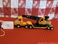Photo of the orange Buddy L crane truck toy showing the left side with extended crane arm and cab details.