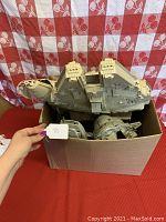 Millennium Falcon ship pieces inside a box, partially assembled with visible dirt and wear