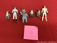Six Star Wars action figures posed on red fabric background with pink post-it note labeled '97'