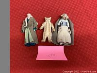 Three Star Wars action figures displayed on red background.