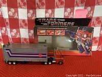 Full semi-truck attached to ribbed silver trailer in front of original box