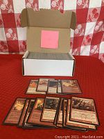 Open white box filled with approximately 400 Magic the Gathering black border cards; a sample of red cards displayed in front showing creatures and spells.