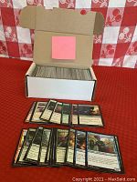 Photo displaying a spread of some Magic: The Gathering cards from the lot, showing a variety of black border cards including creatures, enchantments, and spell cards.