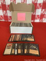 Box of approximately 400 loose Magic: The Gathering cards with a pink sticky note labeled 139 on inside lid. Cards include a variety of colored cards, mostly black-bordered, some visible cards displayed in front in protective sleeves.