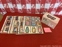Photo of multiple pages of trading cards in plastic sleeves alongside collector storage box labeled 'Wacky Packages'
