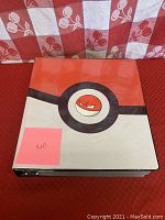 Closed Pokemon-themed binder with Voltorb design on cover photographed on red patterned surface