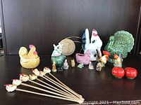 Group photo showing various rooster figurines, Wade animal figurines, bamboo stir sticks, and ceramic pieces including a green turkey-shaped container and tomato salt and pepper shakers.