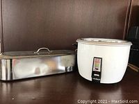 Ten-cup Geneva rice cooker in white next to stainless steel fish poacher with lid on a wooden surface