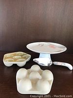 Cake stand, server, and two ceramic molds shown together on dark surface