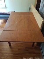 Rectangular teak veneer table top with two built-in extension leaves, showing surface wear and one missing teak edge trim.