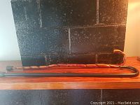 Black cane with smooth finish and curved handle. Brown wooden cane with carved texture and curved handle, both shown side by side horizontally.