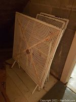 Folded metal table showing mesh top and X-frame support, paint wear visible.