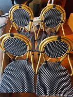 Front view of four bistro chairs, showing natural rattan frames and black and white woven seats and backs