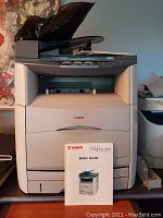 Front view of Canon ImageClass MF8180C multi-function colour printer with user manual placed on front tray.