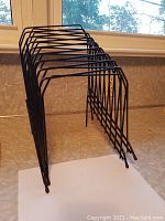 Two black metal wire file organizers set on a counter under a window, used for sorting and holding papers.