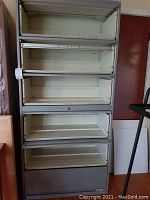 Front view of 6-drawer metal filing cabinet with drawers open, showing perforated metal side panels and lock.