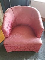 Front view of vintage tub chair showing seat and back with pink damask fabric upholstery and visible wear