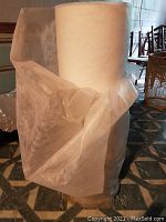 Large roll of white unwoven frost blanket material shown standing upright, partially unwrapped.