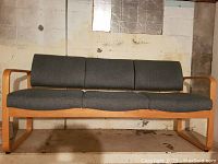 Full view of three-seater bentwood sofa with wooden frame and blue fabric cushions against a beige wall.