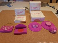 Two sets of Barbie lip gloss and fragrance in purse and hat-shaped containers displayed with their original boxes.