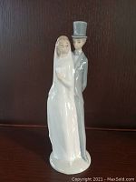 Front view of Lladro bride and groom figurine showing full standing figures and details of dress and suit.