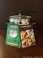 Pressure cooker with lid, including user manual and recipe book in front.