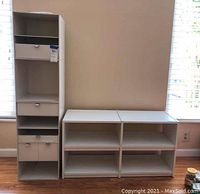 Photo showing the tall vertical shelving unit with drawers and two low horizontal shelves in white melamine against a wall.