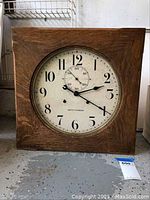 Front view of square oak wall clock showing round dial and seconds subdial