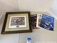 Framed waterfowl stamp print and three Decoy magazines displayed on white background