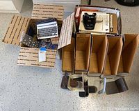 Top view of boxed office supplies including metal bookends, hole punches, stapler and box file dividers.