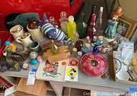 Wide shot of assortment on table showing variety of ceramics, glassware, figurines, and collectibles