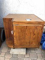 Front angled view of the wood laminate corner table showing wood grain and cabinet door.