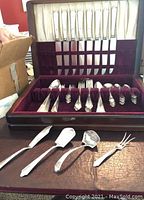 Full view of flatware set inside wood case with some pieces removed