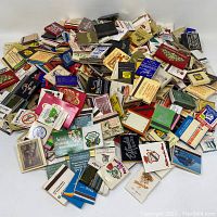 Photo showing a large pile of over 100 vintage matchbooks featuring various California locations and businesses, mostly restaurants and hotels, in assorted colors and designs.