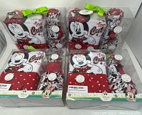 Four boxed sets of Disney Baby Minnie Mouse 5-piece layette clothing sets in packaging, with green ribbon tops, displayed in a box.