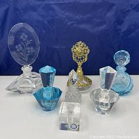 Overview photo showing all six empty vintage perfume bottles in the lot on a white surface with a dark blue fabric background.