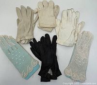 Six vintage gloves displayed on a white surface showing different styles and materials