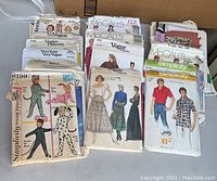 Photo showing assortment of vintage Simplicity, McCalls, and Vogue sewing patterns with illustrated clothing and costume designs on paper envelopes.
