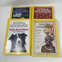Front view of four National Geographic magazines showing different covers including dog, New Guinea, and Saving Energy topics