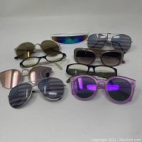 Top-down view showing all nine eyewear items arranged in two rows, highlighting sunglasses with various lens tints and frame styles.