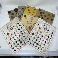 Four cards showing a wide variety of vintage buttons arranged in rows and columns, various colors and styles visible, some handwritten notes on cards.