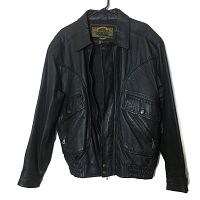 Front view of the black Pelle Global Identity leather jacket showing flap pockets with snaps and zippered compartments, front zip closure, collar, and elastic hem.