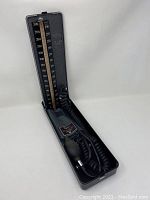 Full view of Baumanometer blood pressure machine with inflation bulb and coiled cord in open hard case showing entire unit.