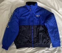 Vintage Fila full-zip jacket in blue and black color blocking with Fila logos on chest and sleeve, laid flat.